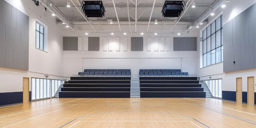 Privat school sports gymnasium with large rectangular acoustic panelling around the walls to absorb reverberation