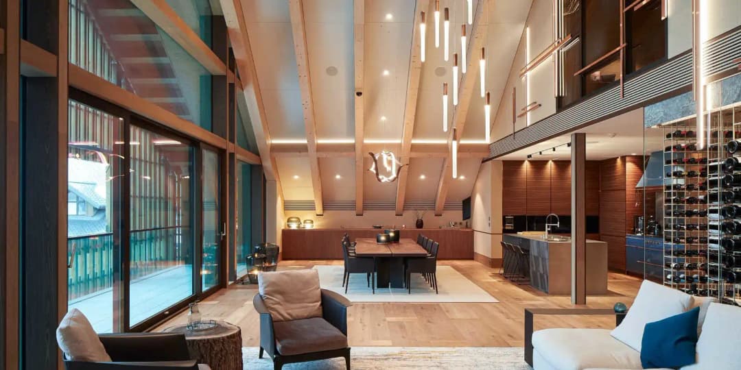 High ceiling open plan living and dining room with acoustic ceiling panels installed between timber beams