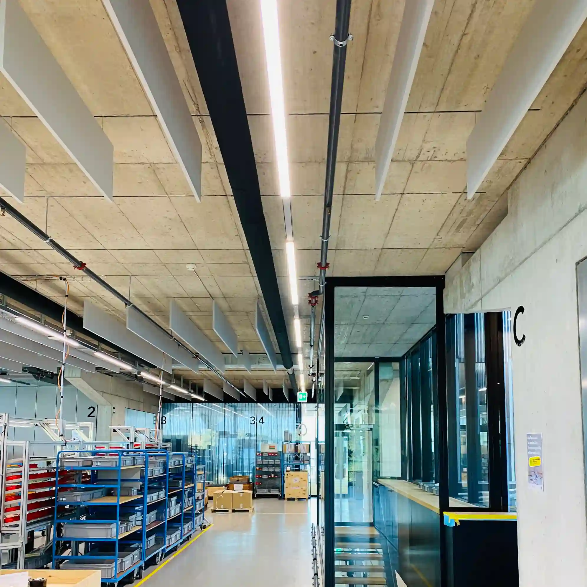 manufacturing facility with concrete floor and ceiling. There a acoustic baffles on the ceiling to dampen mechanical noise