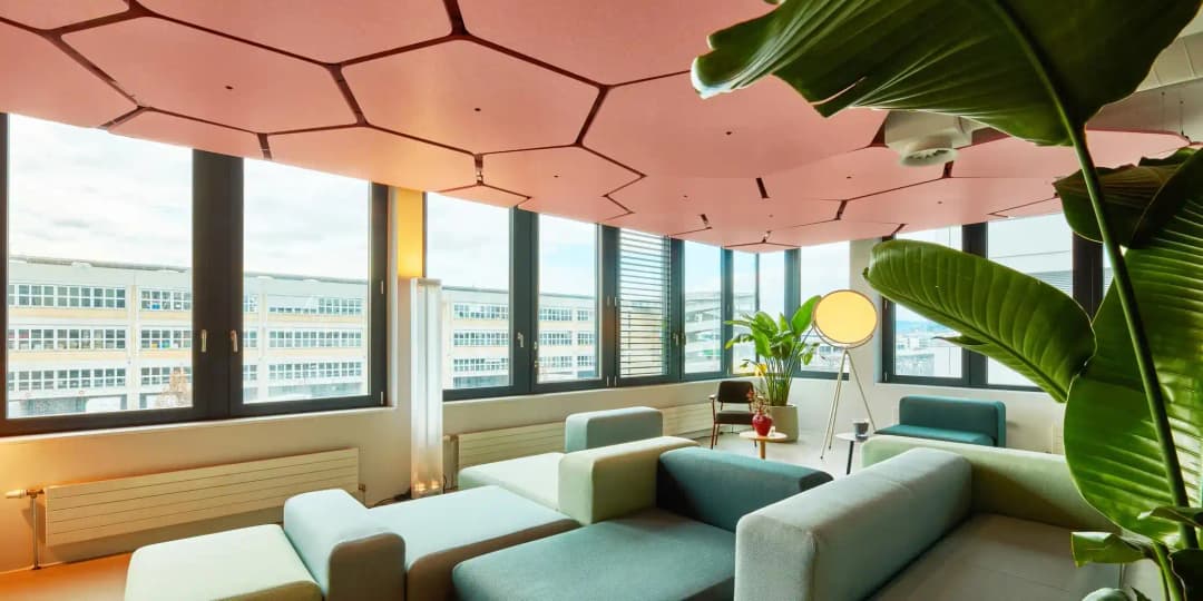 lounge breakout area in commercial space with city views, pink tessellating acoustic rafts suspended from ceiling