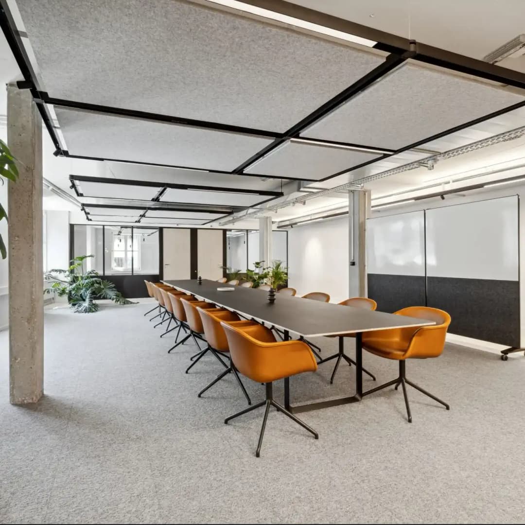 suspended ceiling rafts in metal frame above a modern table in a open meeting room