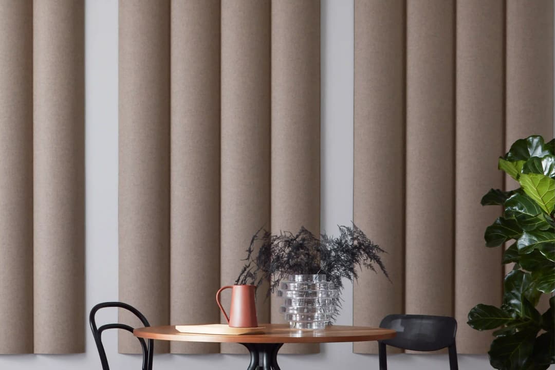view over a restaurant table with flowers on them of a Scala XL acoustic wall panel with large ribs and a fabric wool finish