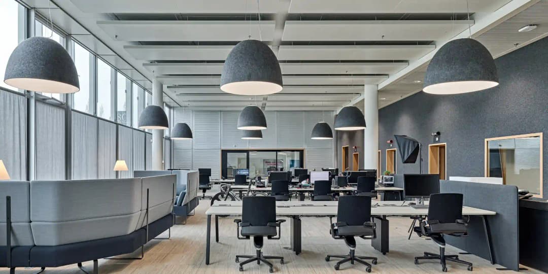 modern office with double height ceiling and large rectangular acoustic panels suspended form the soffit. Neutral tones of grey and white