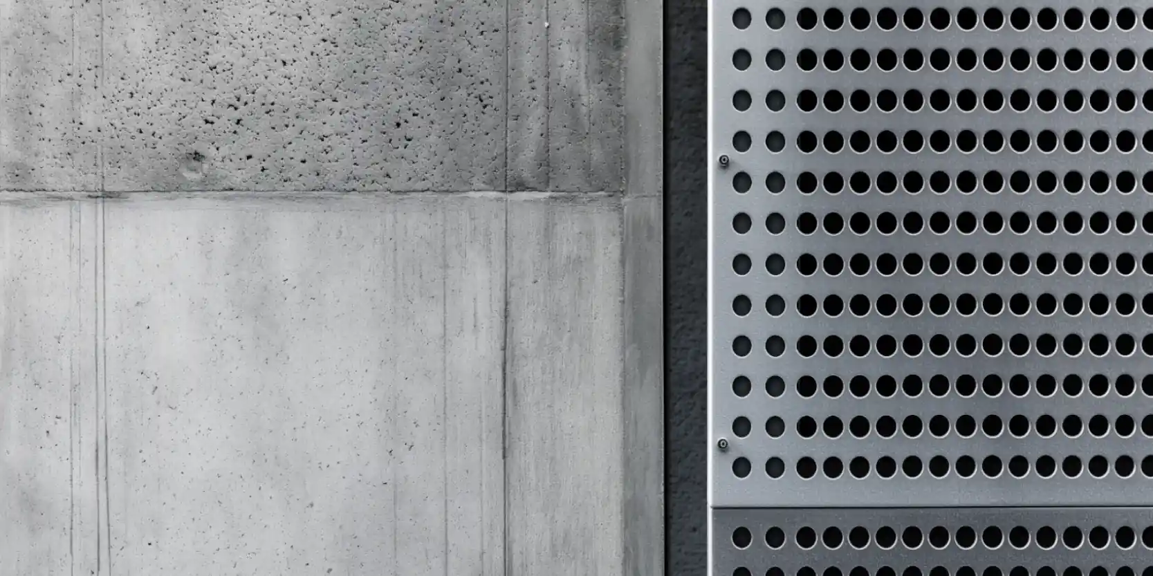 close up of industrial concrete wall with stainless steel metal perforated acoustic panel installed on it