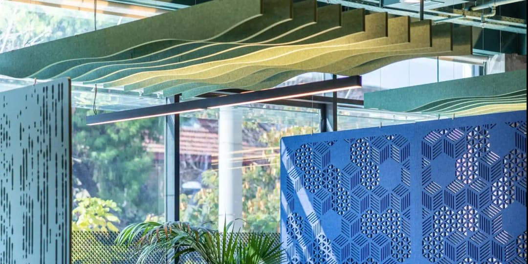 closeup of green acoustic baffles and suspended acoustic screens with pattern cut-outs in an bright and clean office environment