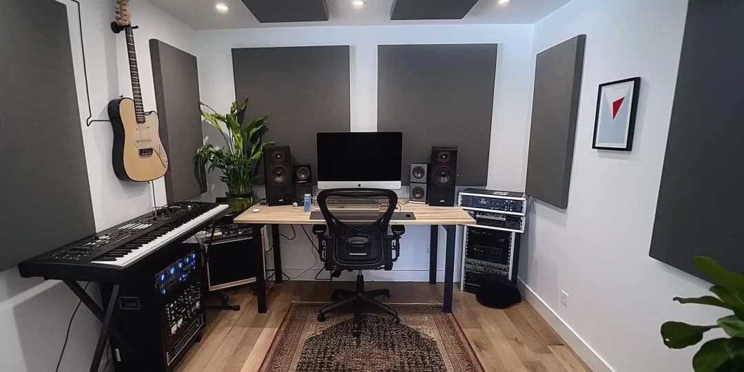 view of a small garden music studio, there is a keyboard and guitar with some fabric wrapped acoustic panels on the wall