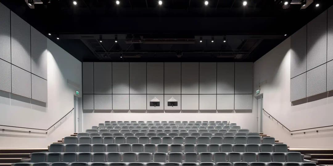 new auditorium and lecture hall with tiered seating and rectangular acoustic wall panels at high level