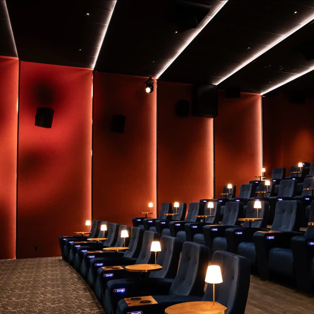 interior shot of a luxury cinema with individual armchairs, high quality acoustic wall and ceiling panels in red with backlit LEDs