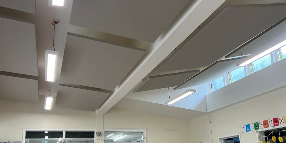 Nursery classroom with suspended acoustic ceiling rafts in grey and small tables for children